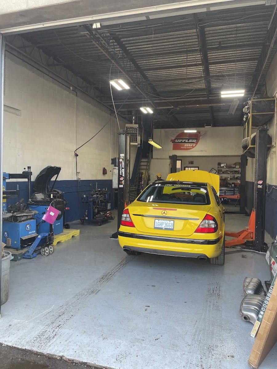 Inside the Muffler Hut bay in North York with a yellow Mercedes on the floor and lifts on either side